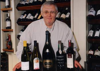 Photograph of Trevor Hughes with a selection of wines.